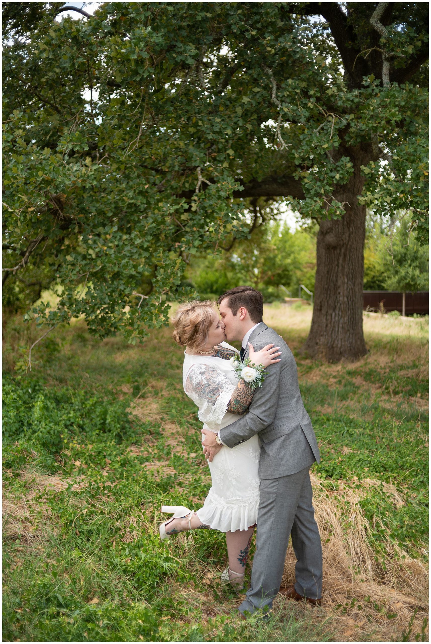 Newly wedding having a passionate kiss under a tree