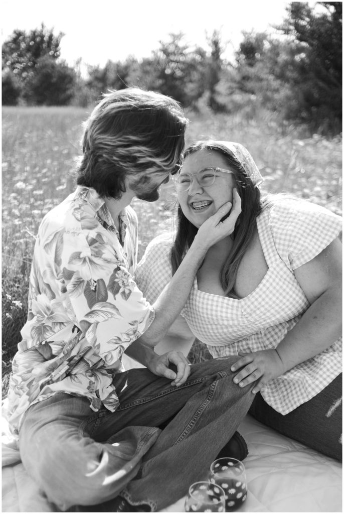 Smiling happy couple in college station for picnic engagement photos. Black & white image of them in a flower feild. 