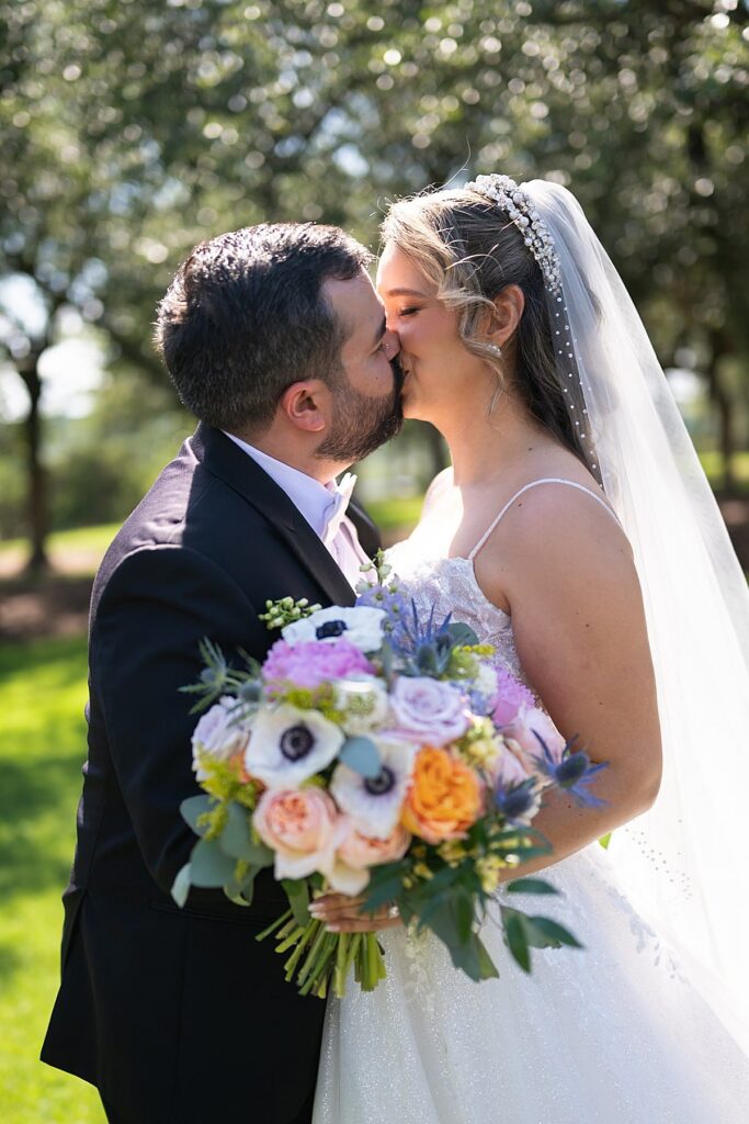 Couple kissing with flower bouquet in the Texas Hill Country. 