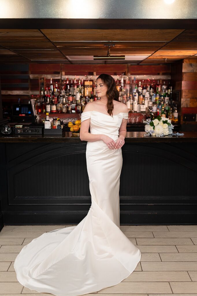 Full Body Photo of a Bride with liquor bottles behind. 
