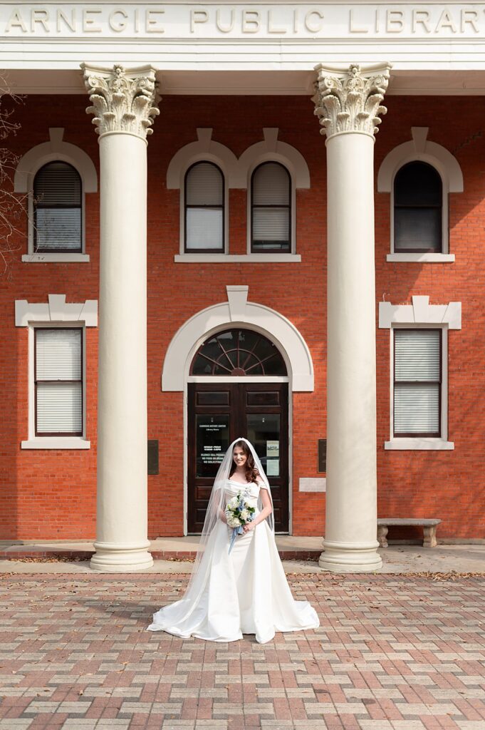 Carnegie Public Library with a bride posing with flowers in front. 
